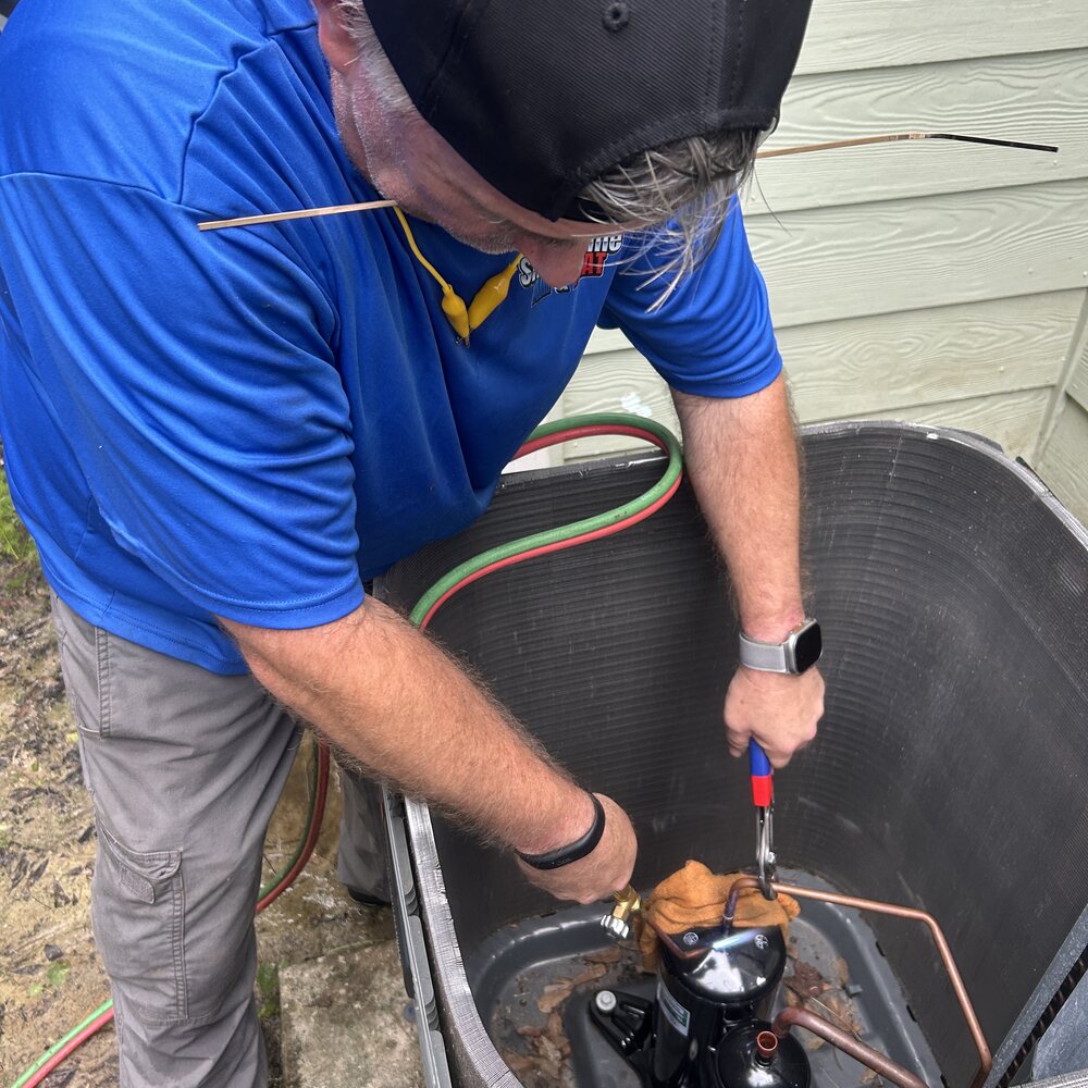 Smart Home Air & Heat tech servicing a compressor